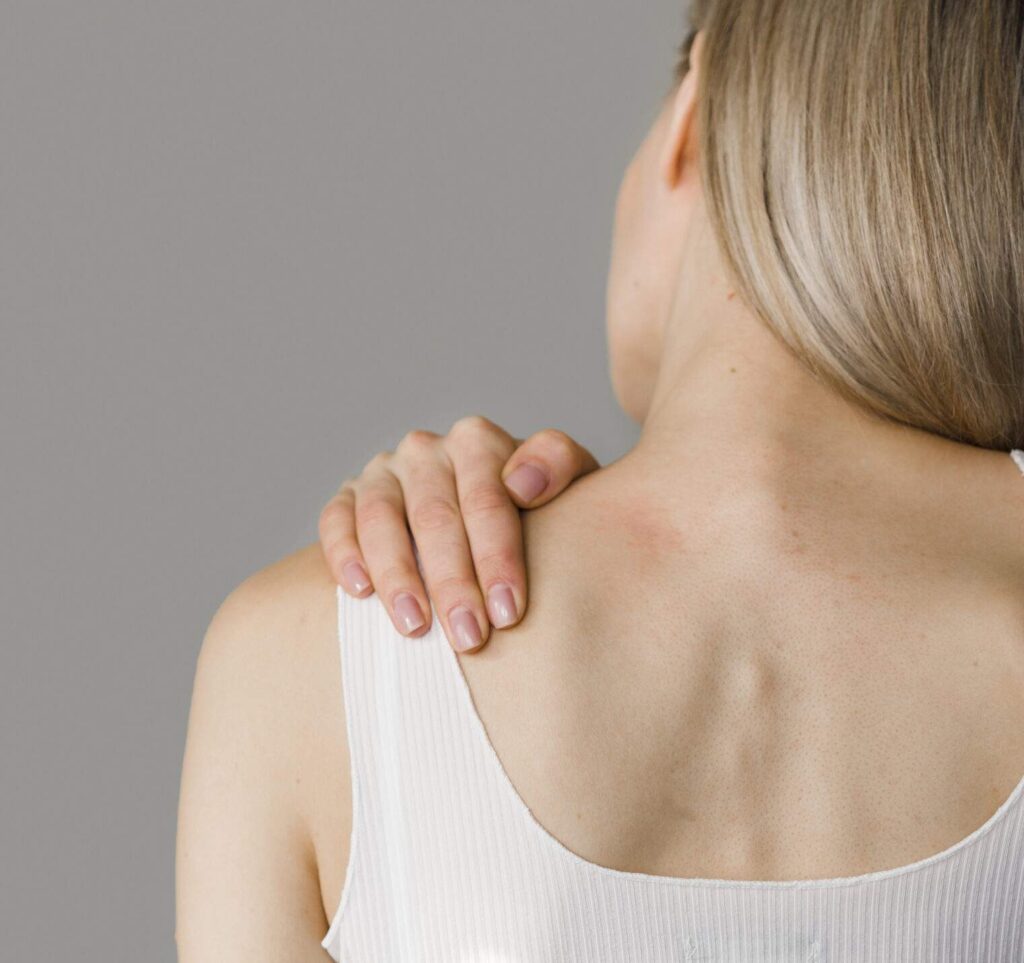 Mujer con dolor de hombro tocándose la articulación en clínica de Alcalá la Real