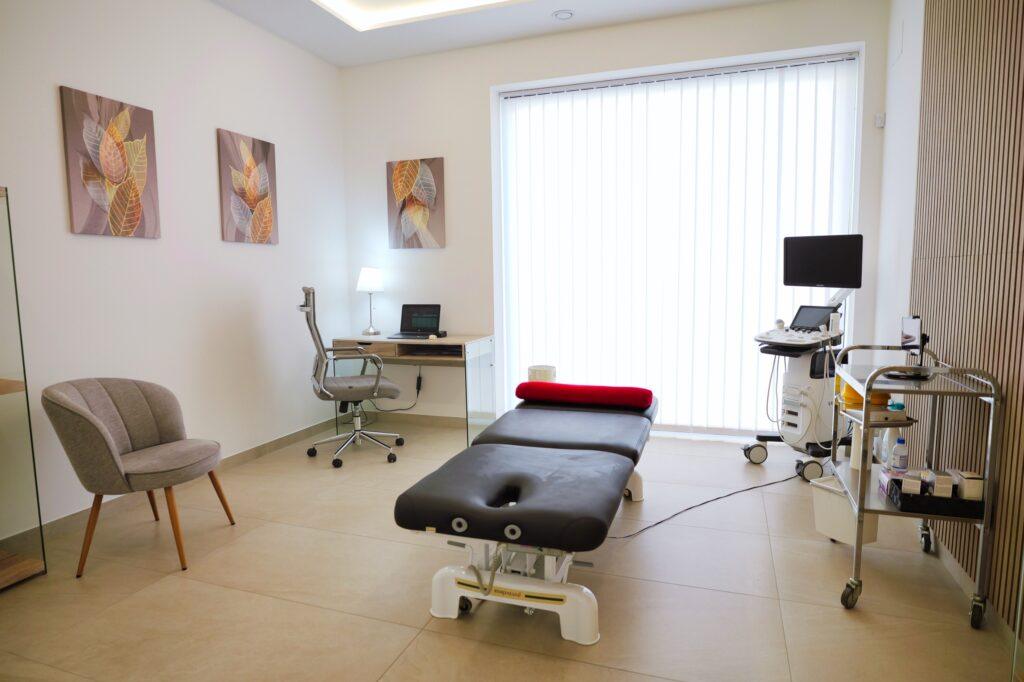 Sala de consulta y tratamiento en Leonardo Estudio de Salud, con camilla, escritorio y un moderno ecógrafo.